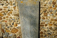 Little Yeldham - St John - Stone Coffin Lid  Leaning against the south wall of nave, by the porch, is an early 13th century coffin lid. It is coped slab with beaded edge, and cross formy with plain scroll arms springing from the middle of the stem. : Church, Essex, Little, Yeldham, St John, C14, C15